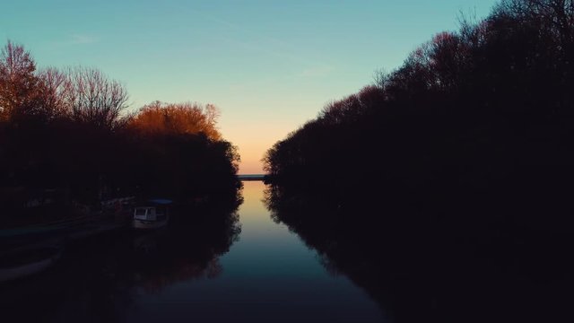 Sunset ovet the river and autumn trees, sailing boat video 