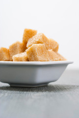 brown sugar cubes on white square dish, dark wood table
