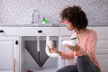 Woman Looking At White Sink Pipe In Hands