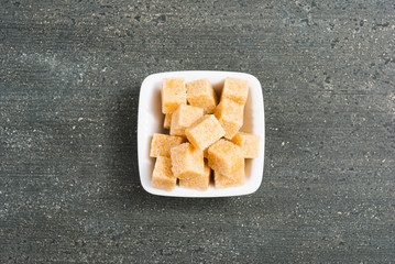 brown sugar cubes on white square dish, dark wood table