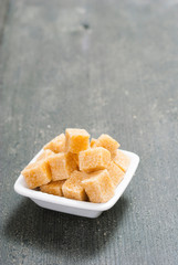 brown sugar cubes on white square dish, dark wood table