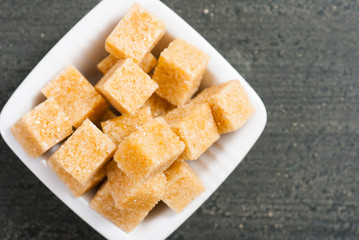brown sugar cubes on white square dish, dark wood table