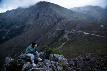 Naklejka na ściany i meble Man sitting on rocks above long road in mist