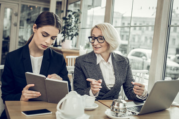 Successful blonde-haired businesswoman talking to her young trainee