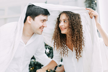 Naklejka premium Young couple embracing and sitting in front of a mirror. Photo shoot in bright interior Studio in European style.