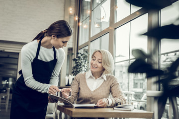 Mature blonde-haired woman making order in the restaurant