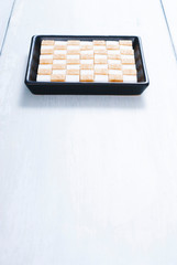 white and brown sugar nubs on black square plate, bright wood table background