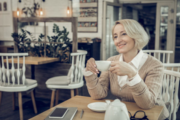 Beautiful mature woman sitting in cafeteria waiting for her husband