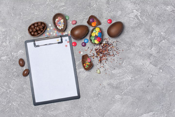 Mock up of clipboard and chocolate traditional easter eggs with bright colorful dragee