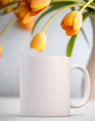 White Mug Mockup - Easter theme. Blank white mug next to pretty orange tulips. Perfect for businesses selling mugs, just overlay your quote or design on to the image.	