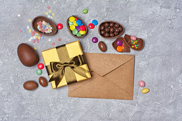 Chocolate traditional easter eggs and golden gift box with kraft envelope