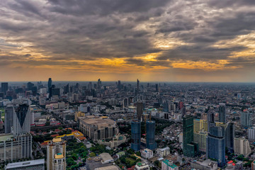 Aerial view of Bangkok skyline and skyscraper with light trails at sunset.
