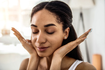 Delighted brunette female person demonstrating her face