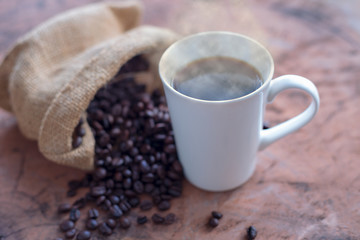 Coffee in a white cup and coffee beans on a wooden table
