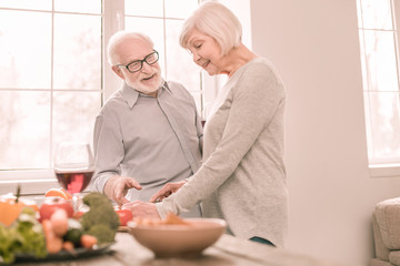 Cheerful blonde woman cooking salad for dinner