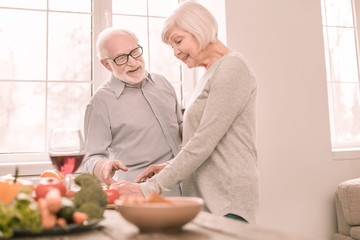 Obraz na płótnie Canvas Cheerful blonde woman cooking salad for dinner