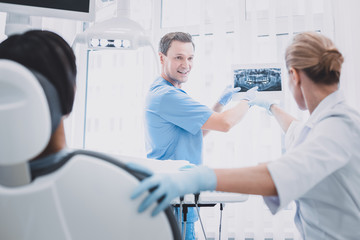 Obraz premium Cheerful male person demonstrating x-ray picture to colleague