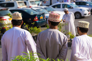 Three Omani men shoulders in traditional clothes with dishdasha and kuma