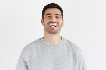 Fototapeta premium Laughing out loud concept. Young man in smiles broadly, laughing, showing perfect white teeth