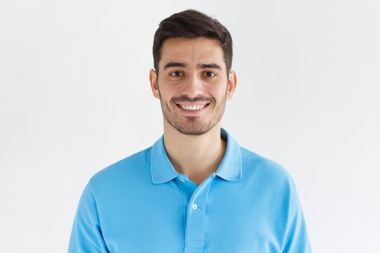 Close Up Portrait Of Young Smiling Handsome Man In Blue Polo Shirt Isolated On Gray Background