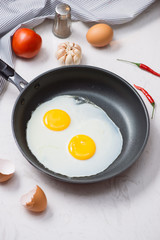 Eating in the process, fried eggs in a frying pan for breakfast on a white background. Daylight.