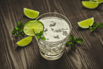 Glass of water with lime, ice and mint. Isolated on wooden background.