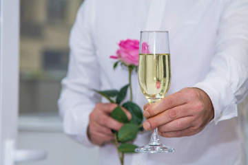 Valentine's day, man with red rose and glass of champagne, romantic surprise.