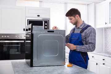 Male Repairman Repairing Oven