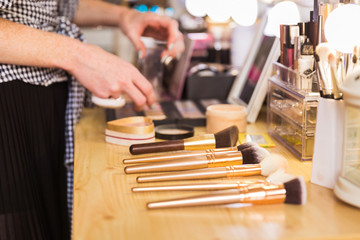 Close-up of the makeup artist taking the makeup brushes from the table indoors