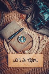 let's go travel message written on card and traveler accessories on wood background