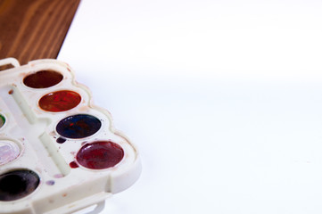 A white sheet of paper lay on a wooden table, near , pencils, paints and markers. Back to school....