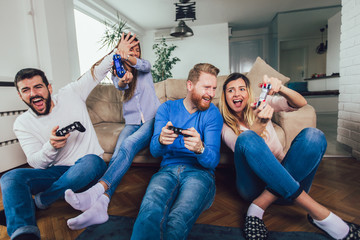 Group of friends play video games together at home, having fun.