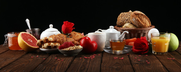 breakfast on table with bread buns, croissants, coffe and juice on valentines day.