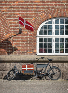 Denmark, wheel of loads in front of red brick house with flag