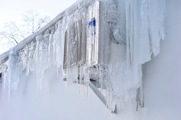 The back of the supermarket building has air conditioning on the wall covered with a thick layer of icicles.