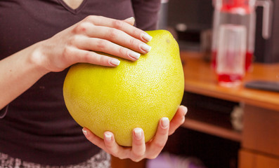 A woman holds in the hands of pomelo. Fruits rich in vitamins_