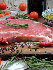 Raw meat steak, pepper, herbs, garlic and knife on wooden chopping board
