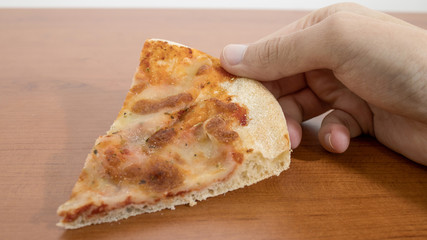 Taking a slice of pizza on a wood table