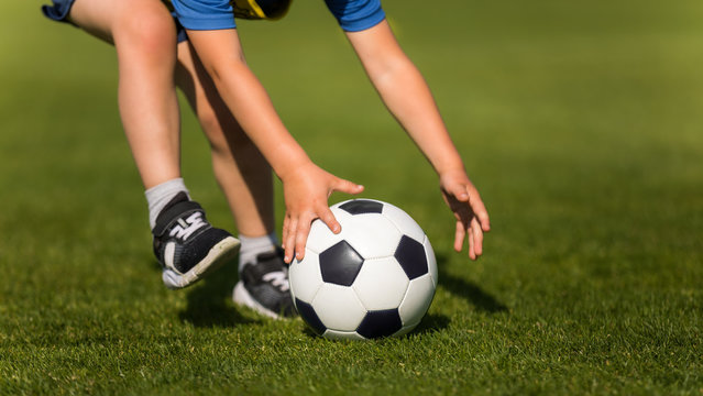 Child playing soccer. Preschool soccer leagues. Kid catching soccer ball on the field. Closeup soccer picture