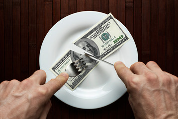 A man cuts a hundred dollars bill. Top view of a dish with dollars. - 244167208