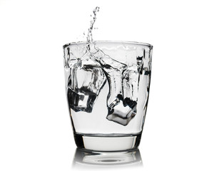 Ice cubes splashing into glass of whiskey isolated on white. brandy in glass with ice. alcohol. liqueur glass