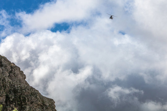 A rescue helicopter flying in a white cloudy sky. Mountains and 
