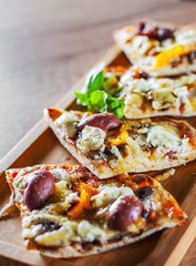 sliced vegetarian pizza with Mozzarella cheese, olives, mushrooms, pepper and fresh basil. Italian pizza on wooden table background