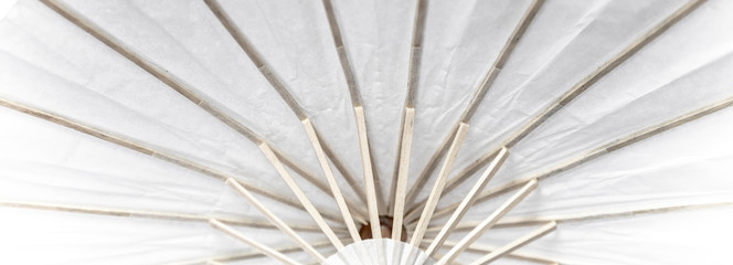 a fragment of umbrella construction made of wood and white paper