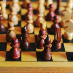 wooden chess pieces on a chessboard outdoor at the sunny day, king in focus
