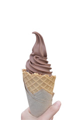 Chocolate ice cream (softserve) waffle cone is holded by left hand, isolated on white background.