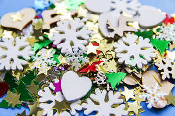 Obraz na płótnie Canvas Christmas and New Year decorative background with small wooden snowflakes. Colorful tinsel. Festive confetti.