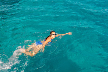 Woman swimmer swimming crawl in blue sea. Woman swiming in the sea. Happy young woman in a blue swimsuit in the sea on vacation. copy space