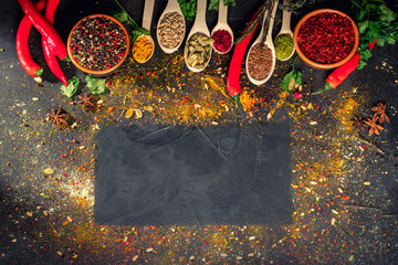 A set of spices and herbs on black stone plate. Top view with free space for menu or recipes
