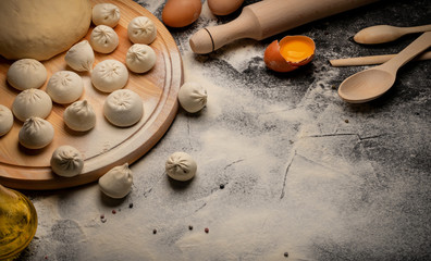 Hinkali homemade. Flour, eggs, dough on a black background. Top view